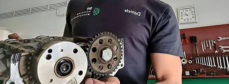 Ingranaggi della distribuzione di un motore smontato, davanti al pannello attrezzi rosso dell'officina